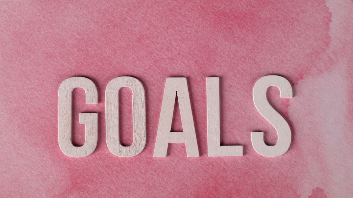 Motivational word 'GOALS' on a pink watercolor background for inspiration.